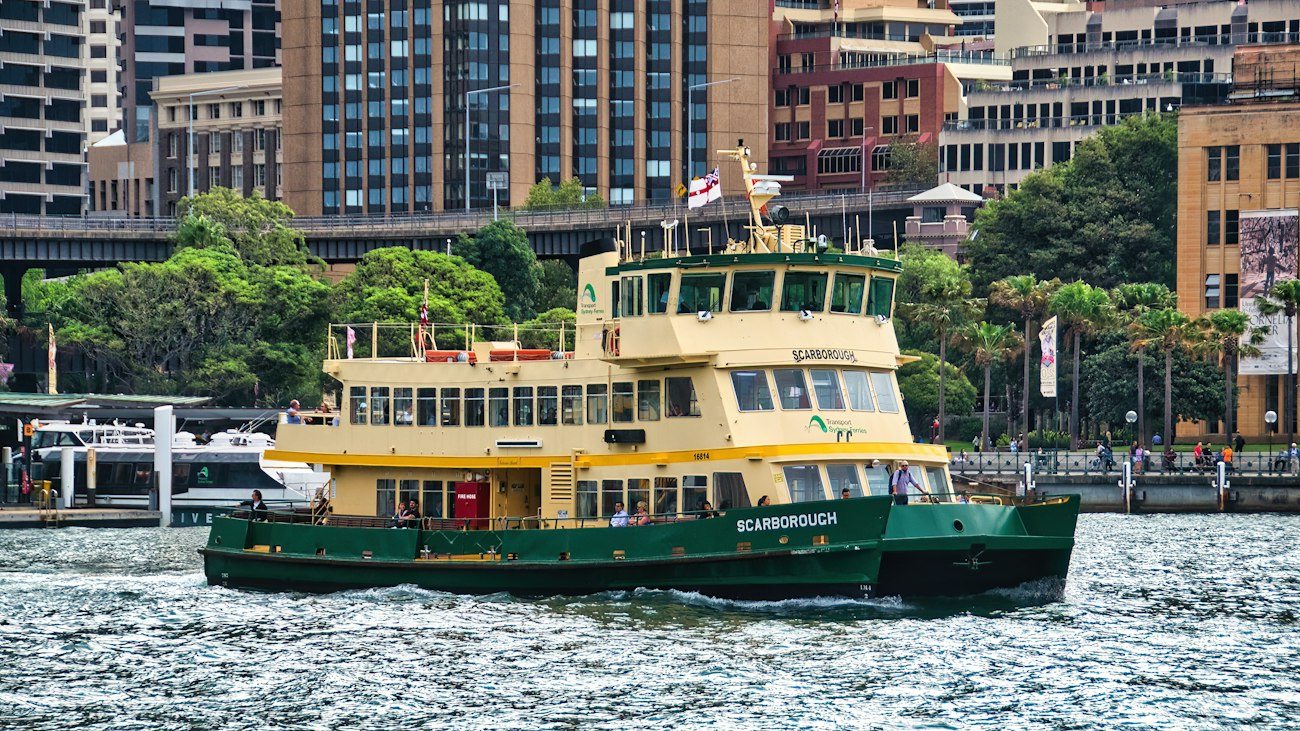 A yellow and green Sydney ferry crossing the harbour