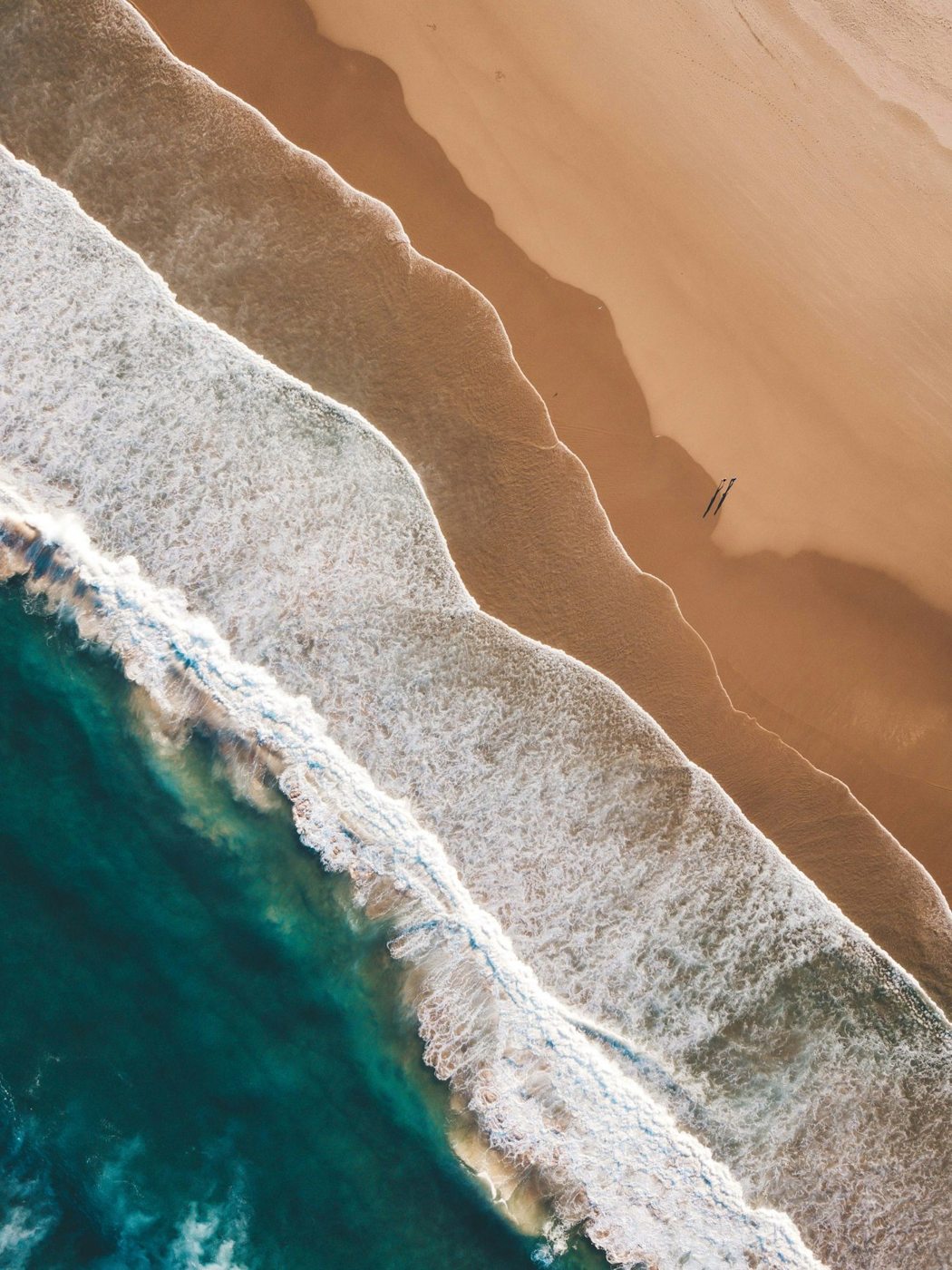 Waves meeting a golden beach near Port Macquarie, seen from above