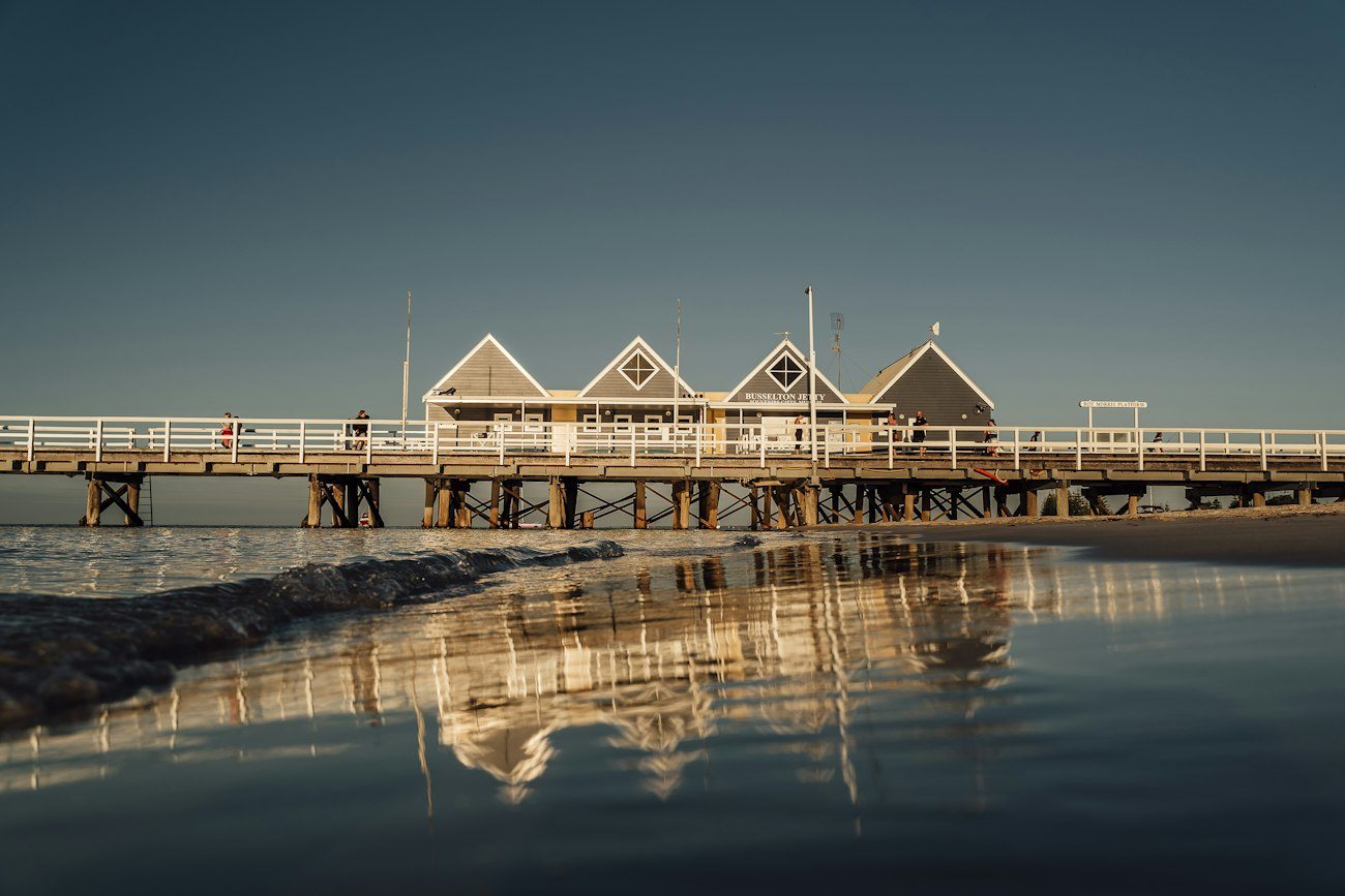 Busselton Jetty and its buildings reflected in still water
