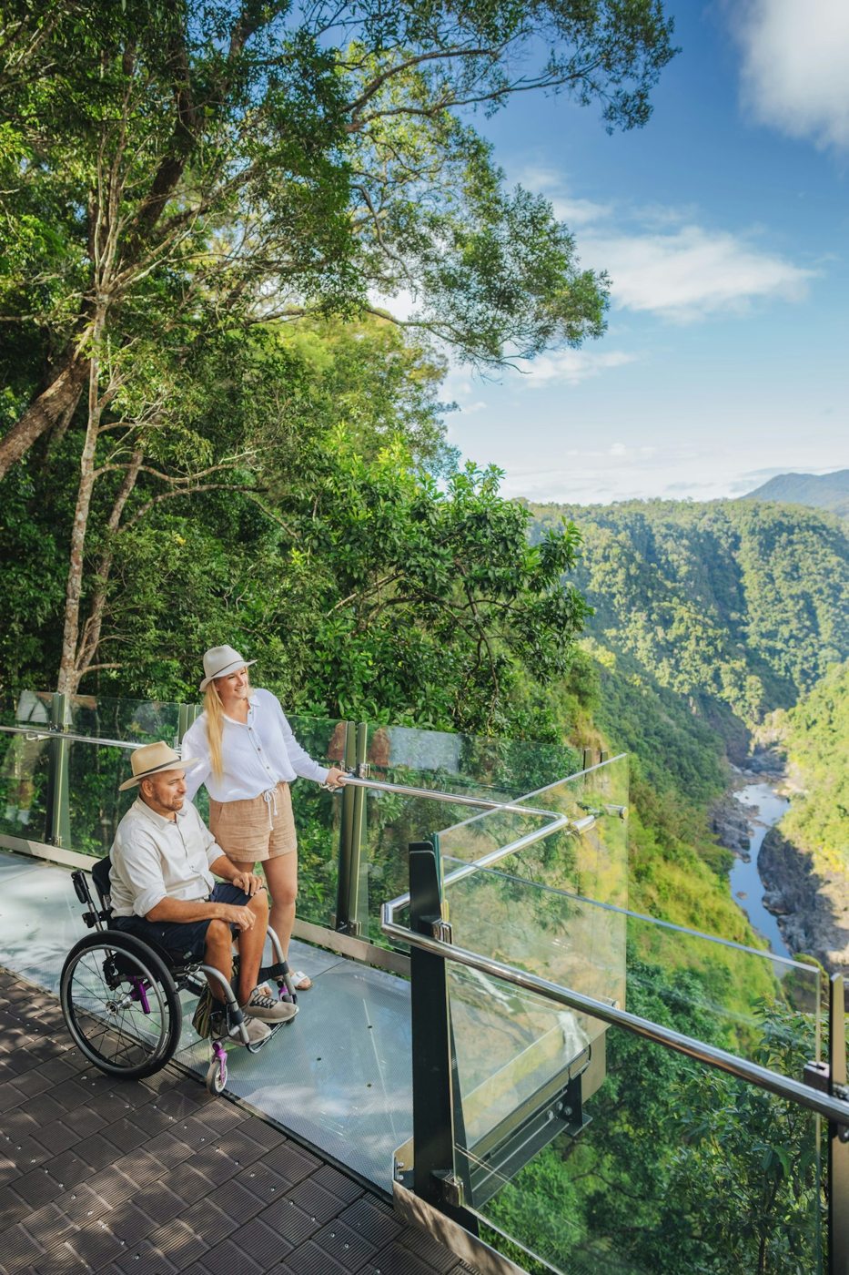 A wheelchair user and companion at a forested lookout