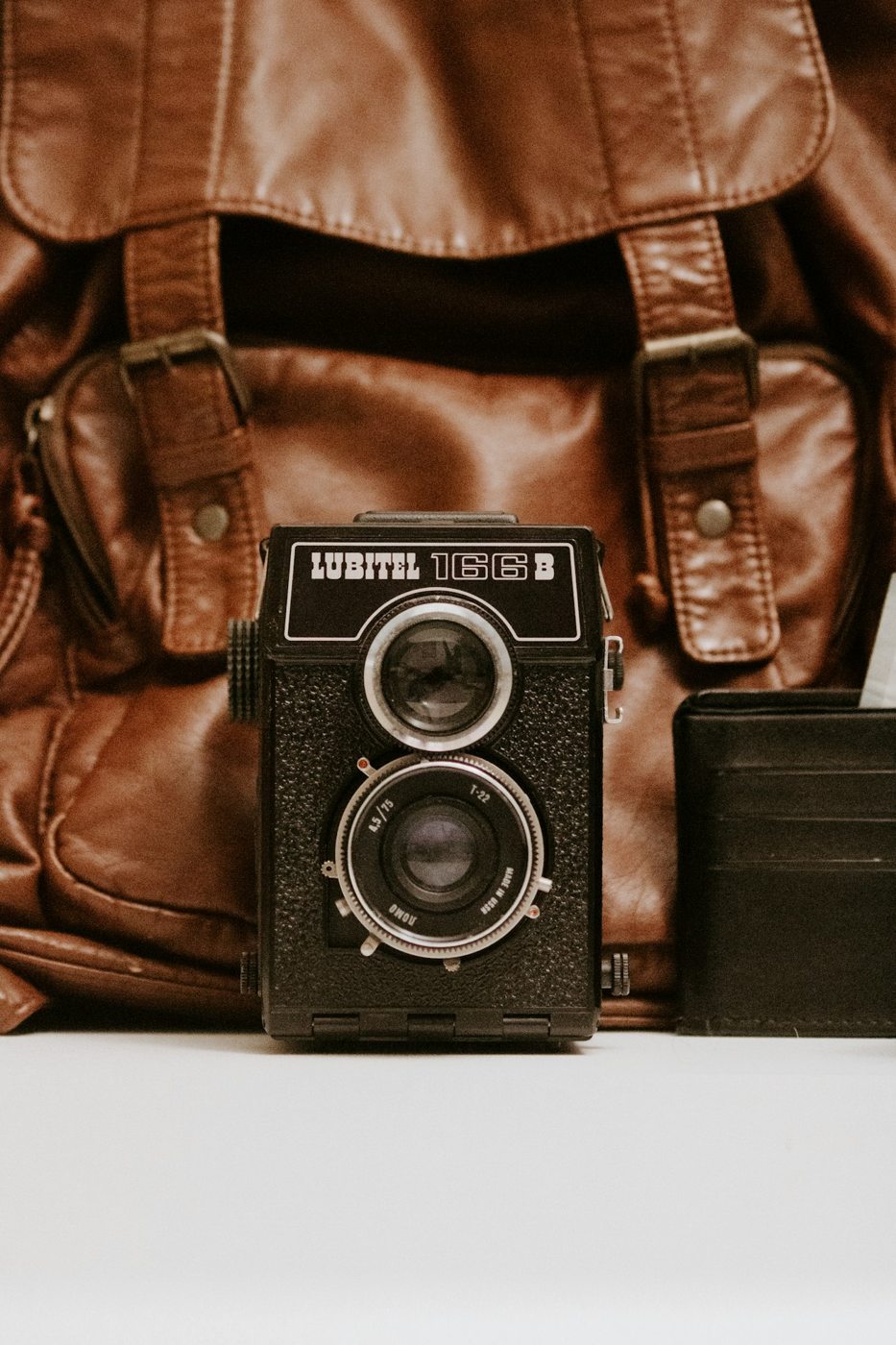 A small twin-lens camera beside a leather camera bag
